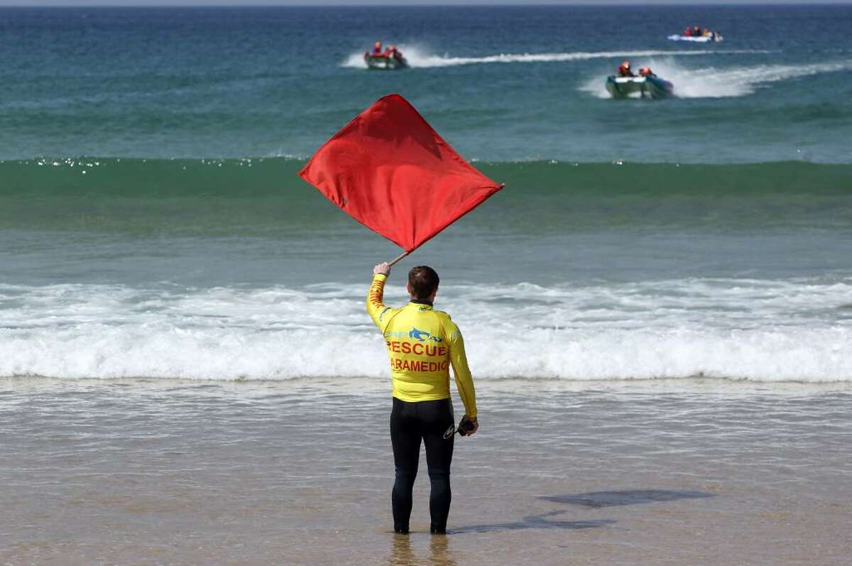 NEWQUAY, ENGLAND - APRIL 23: A red flag is waved from the beach as Zapcat power boats practice in the surf at Fistral Beach on April 23, 2010 in Newquay, England. Cornwall's Newquay is this weekend playing host to the Blue Chip Zapcat Grand Prix where small inflatable catamaran powerboats built for speed with 50hp engines, will battle it out in the national championship. (Photo by Matt Cardy/Getty Images)