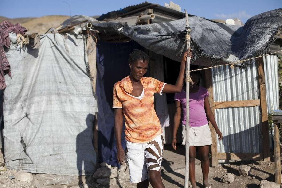 Rosena Dordor, 40, stands in front of her one-room shack in the arid hills north of the Capital in Port-au-Prince, Haiti, Friday, Jan. 9, 2014. Today, nearly five years after the devastating 7.0 earthquake that shook Haiti, Dordor lives with her husband and three children in a one-room shack with a plastic tarp for a roof and walls made of scrap metal and salvaged wood. It’s perched on a cactus- and scrub-covered hillside, a long walk from the nearest source of water, and meals are cooked over fire pits. ( AP Photo/Dieu Nalio Chery)