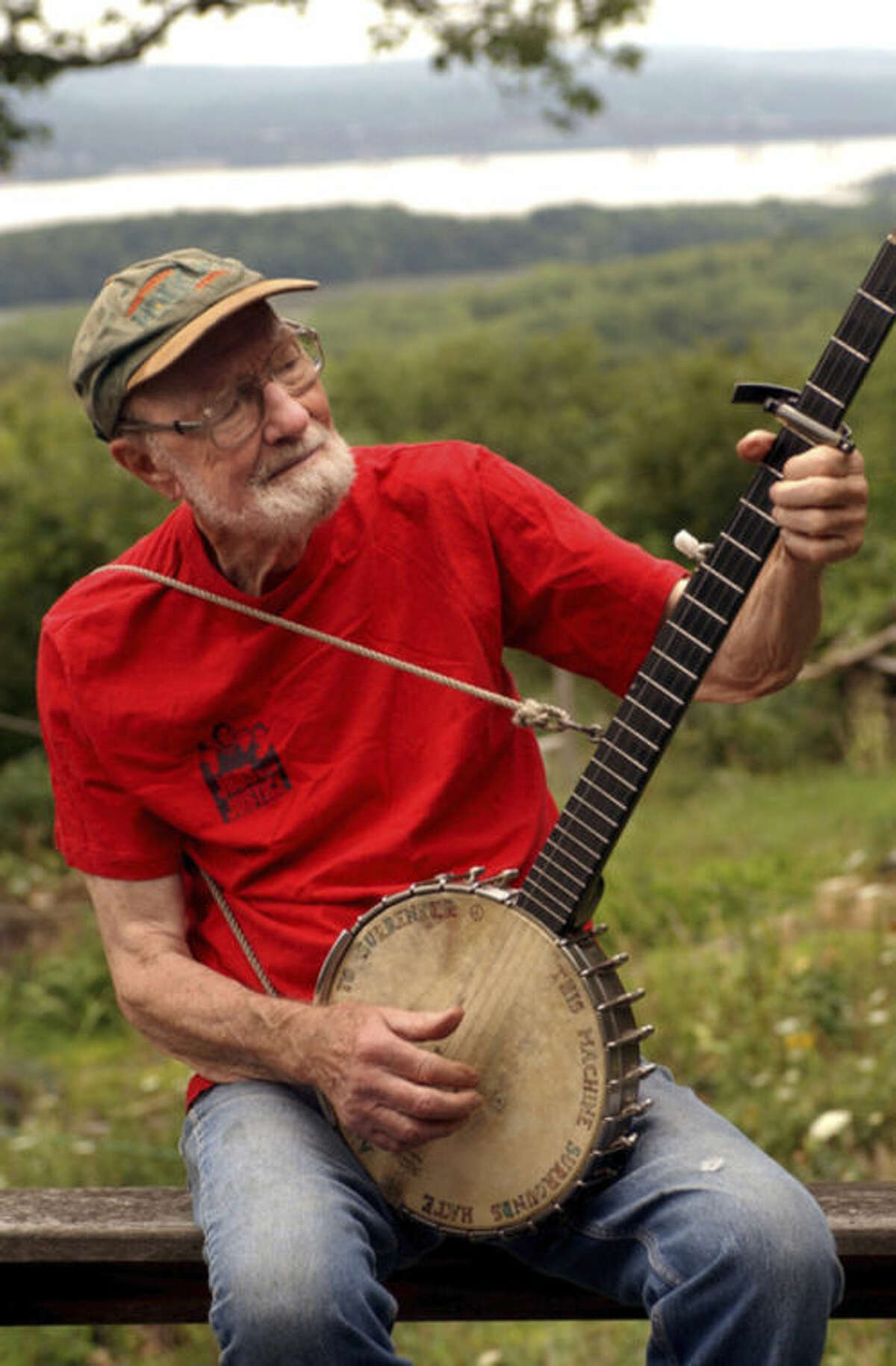 FILE - In this Tuesday, July 27, 2004 file photo, Pete Seeger, 85, sits on his porch above the Hudson River at Beacon, N.Y. and plays a Woody Guthrie song on his banjo. Seeger died on Monday Jan. 27, 2014, at the age of 94. (AP Photo/Jim McKnight)