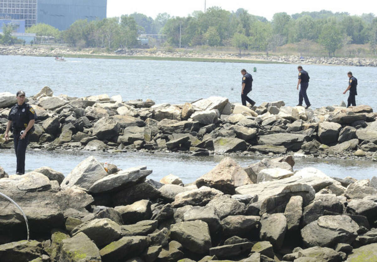 Norwalk police search the shoreline at Calf Pasture Beach Monday where one of four boaters went missing after the boat turned over. Hour photo/Matthew Vinci