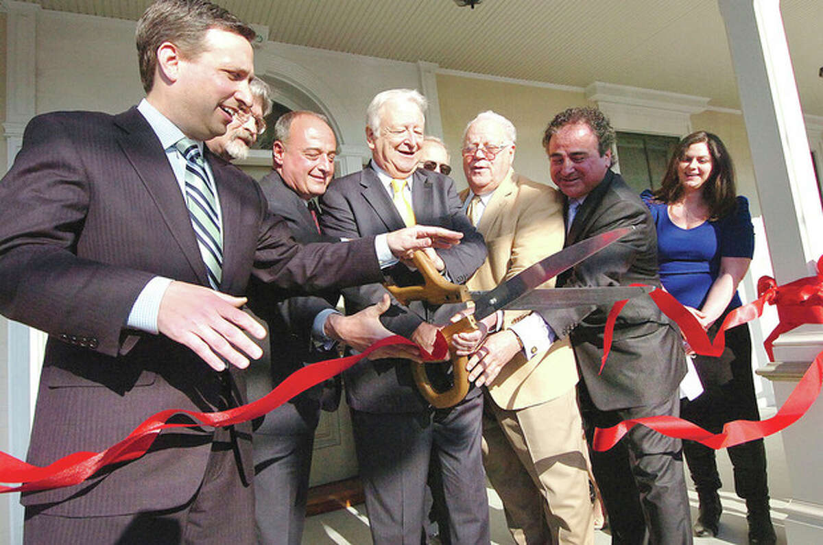Hour photo / Alex von Kleydorff Mayor Richard A. Moccia, surrounded by dignitaries, cuts the ribbon in front of the Grumman St. John House at the Norwalk Inn and Conference Center on Monday.
