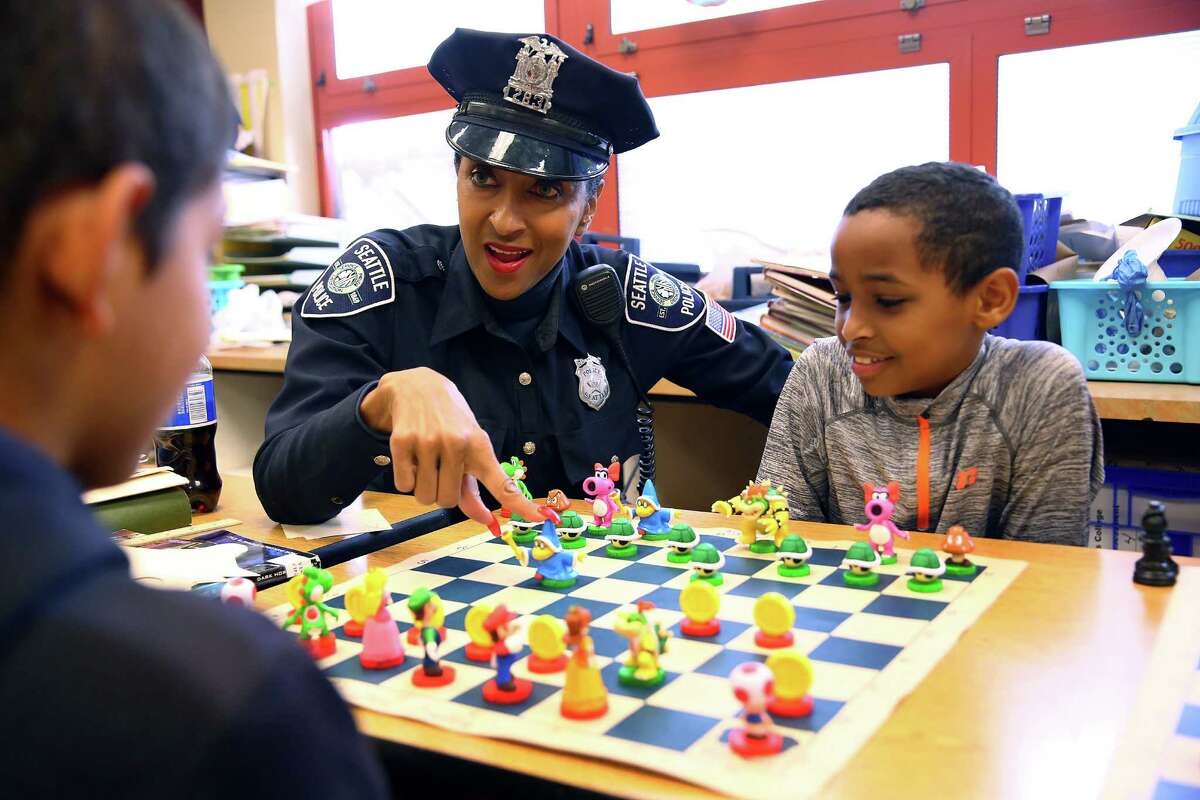 Detective Denise "Cookie" Bouldin talks through a chess game with Van Asselt Elementary students Kaijon Roe, 10, and Sulayman Hussien, 10, during their lunch break, June 2, 2016. Bouldin teaches chess at Van Asselt and South Shore K-8 several time a week, including stopping in at lunch to play with the students. 