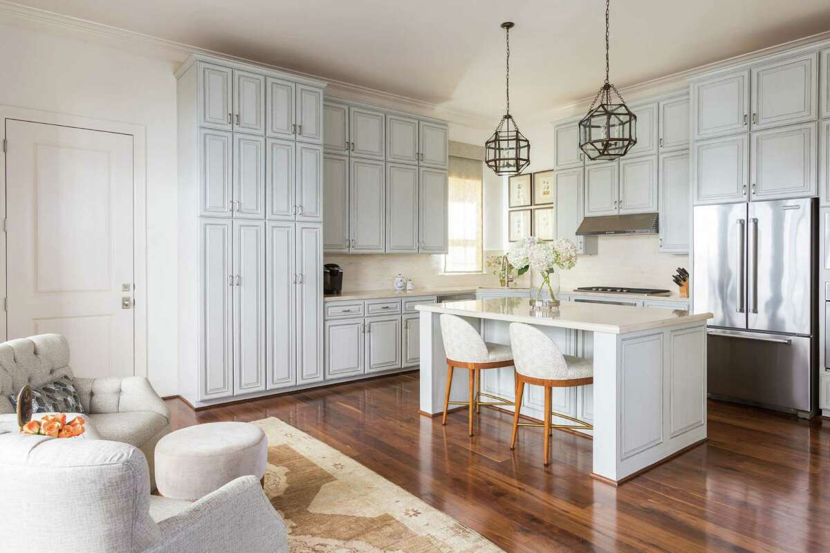 Dark kitchen cabinets were painted pale gray and then treated with antiquing finishes and silver trim.