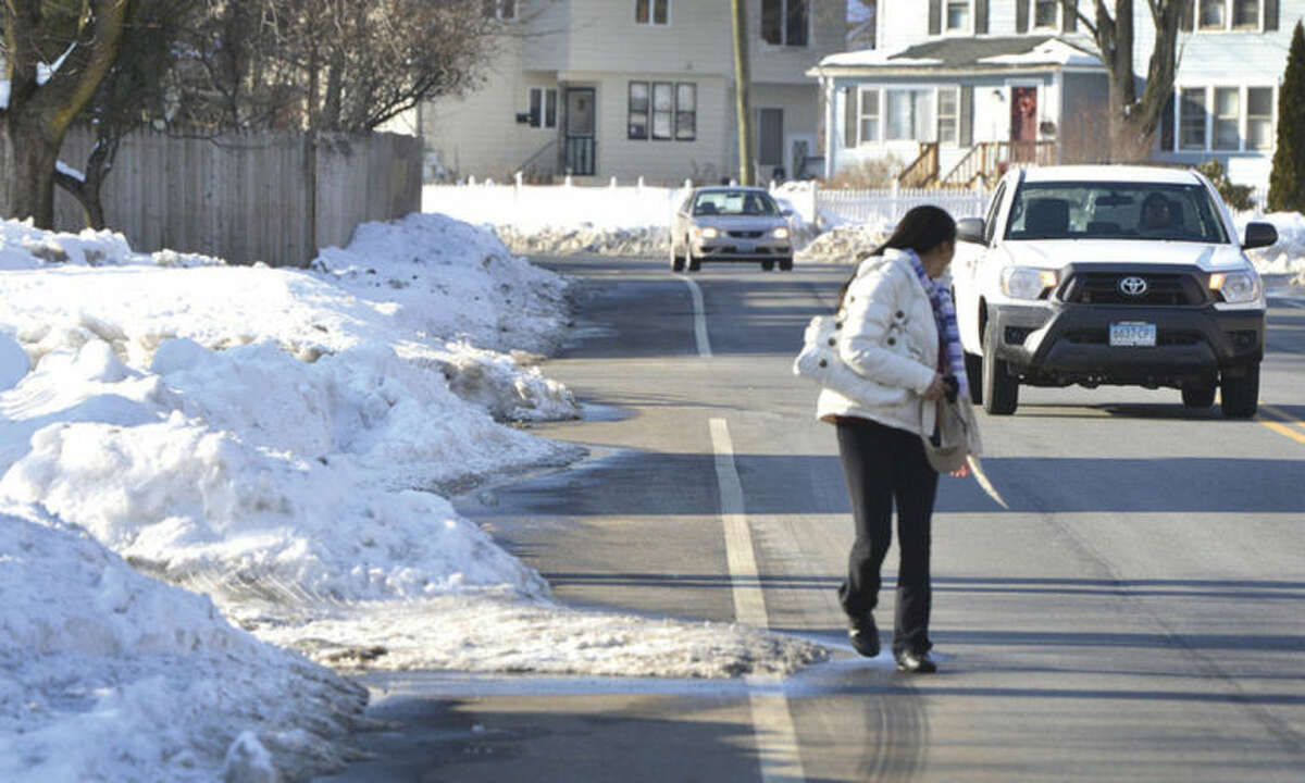 Hour Photo/Alex von Kleydorff. A pedestrain looks for traffic while walking on the side of the road due to sidewalks not being cleared in Norwalk Monday