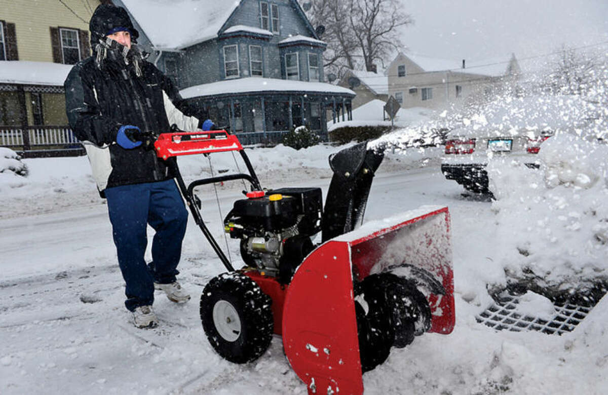 Hour photo / Erik Trautmann Norwalk resident Antonio Migliaccio clears the sidewalks in front of his residents as snow accumulations reach an inch Thursday monring.