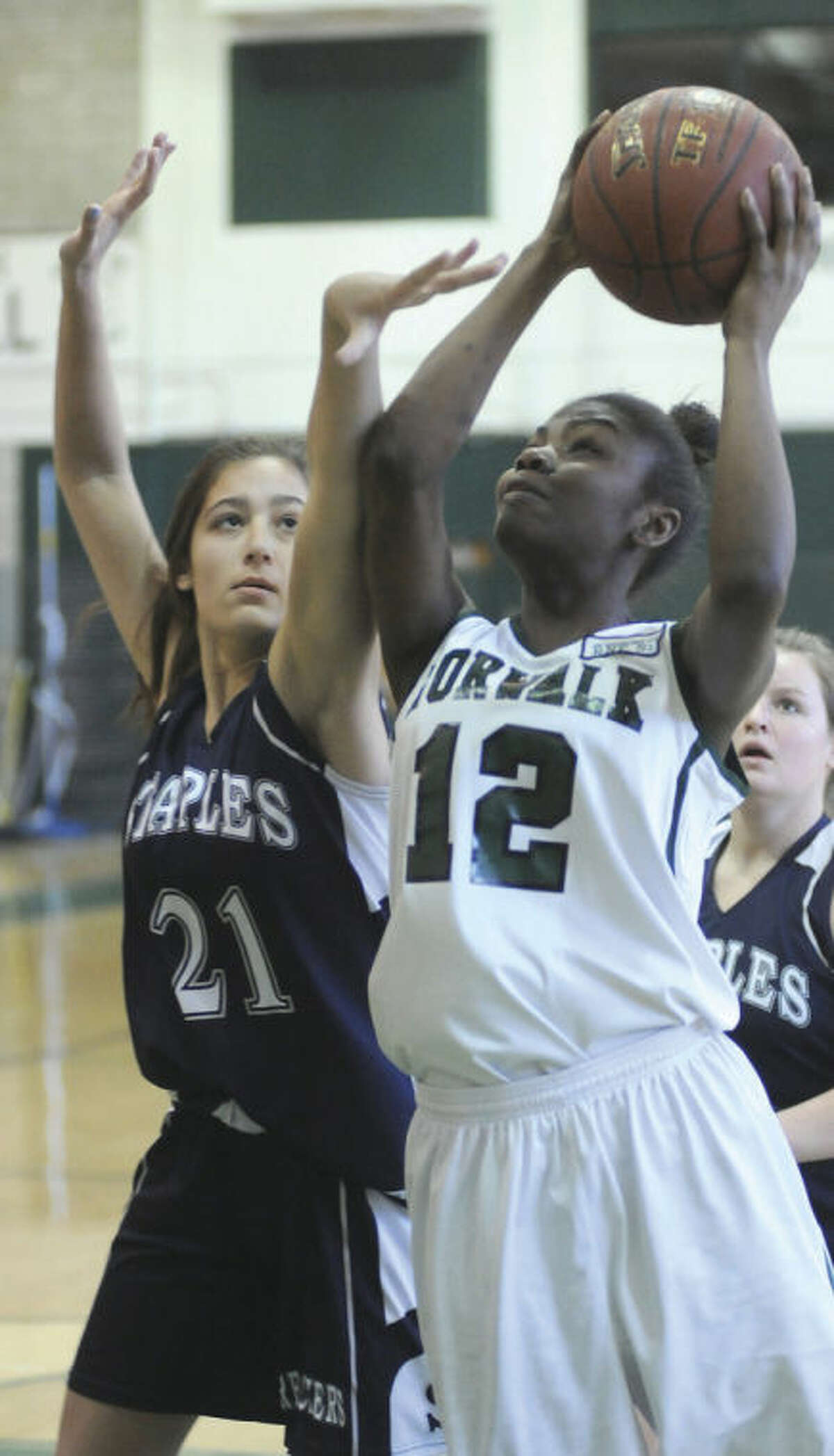 Hour photo/John Nash Norwalk's Asiah Knight (12) powers up to the basket against the defense of Staples' Julie Bartimer during Monday's FCIAC girls basketball game at Norwalk.