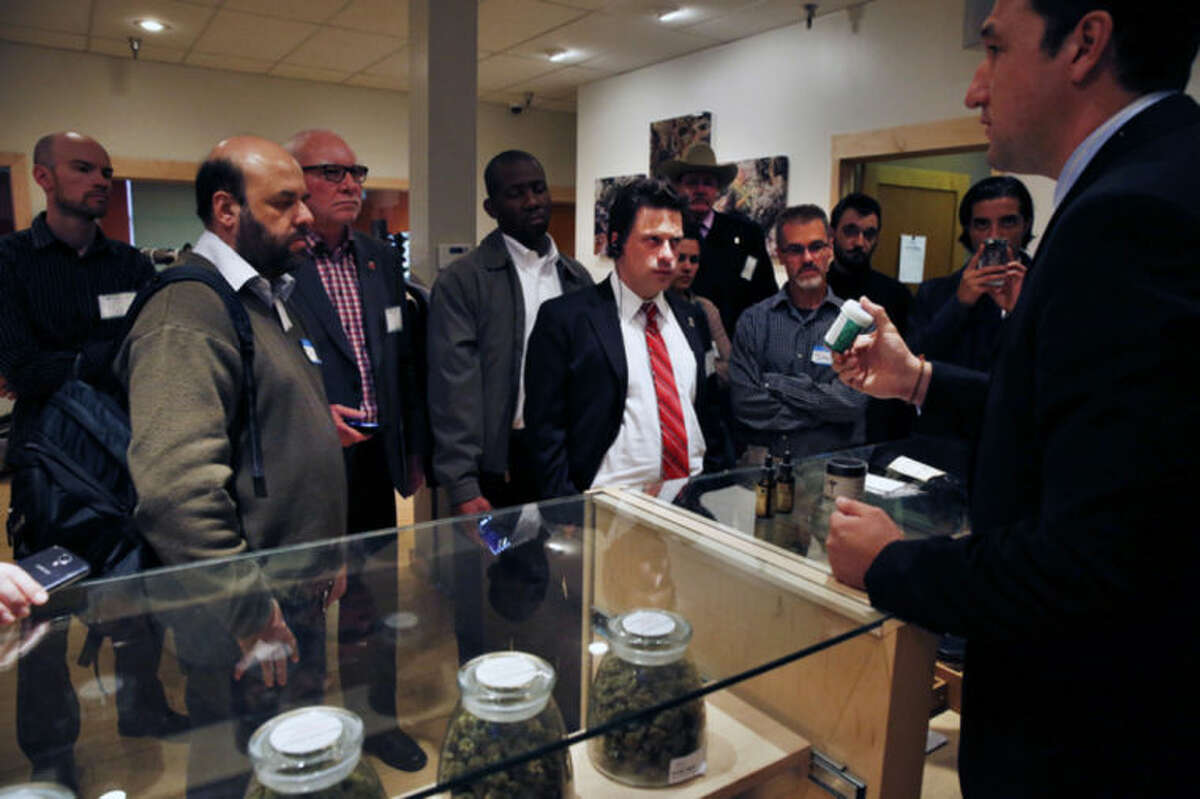 ADVANCE FOR USE SUNDAY, FEB. 16, 2014, AND THEREAFTER - FILE - In this Oct. 23, 2013, Norton Arbelaez, right, the owner of River Rock marijuana dispensary, shows his products to foreign lawmakers, Julio Bango, of Uruguay, second from left, Larry Campbell, of Canada, third from left, and Fernando Belaunzaran, of Mexico, fifth from left, during a tour of his business in Denver. Several foreign lawmakers pushing for drug law reforms at home took a close up look the evolving legal marijuana industry in Colorado. Washington and Colorado passed recreational laws in 2012 to regulate the growth and sale of taxed pot at state-licensed stores. Sales began Jan. 1 in Colorado, and are due to start later this year in Washington. Twenty states and the District of Columbia also now have medical marijuana laws. (AP Photo/Brennan Linsley, File)