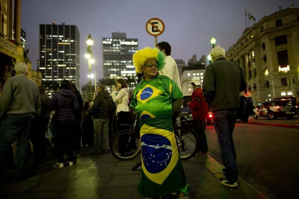 A man dressed in an outfit with Brazilian flags motifs stands on downtown corner in Sao Paulo, Brazil, Tuesday, June 10, 2014. The 2014 World Cup is set to begin Thursday, with Brazil and Croatia competing in the opening match in Sao Paulo. (AP Photo/Rodrigo Abd)