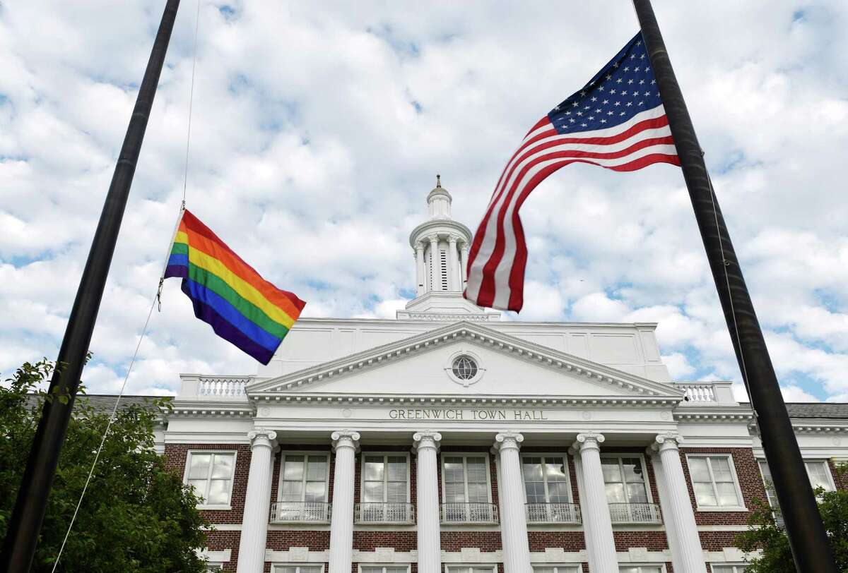 A rainbow-colored flag waves beside the American flag after the LGBT flag-raising ceremony at Town Hall in Greenwich on Monday to honor the victims killed in the shooting at Pulse, a gay Orlando nightclub, over the weekend.