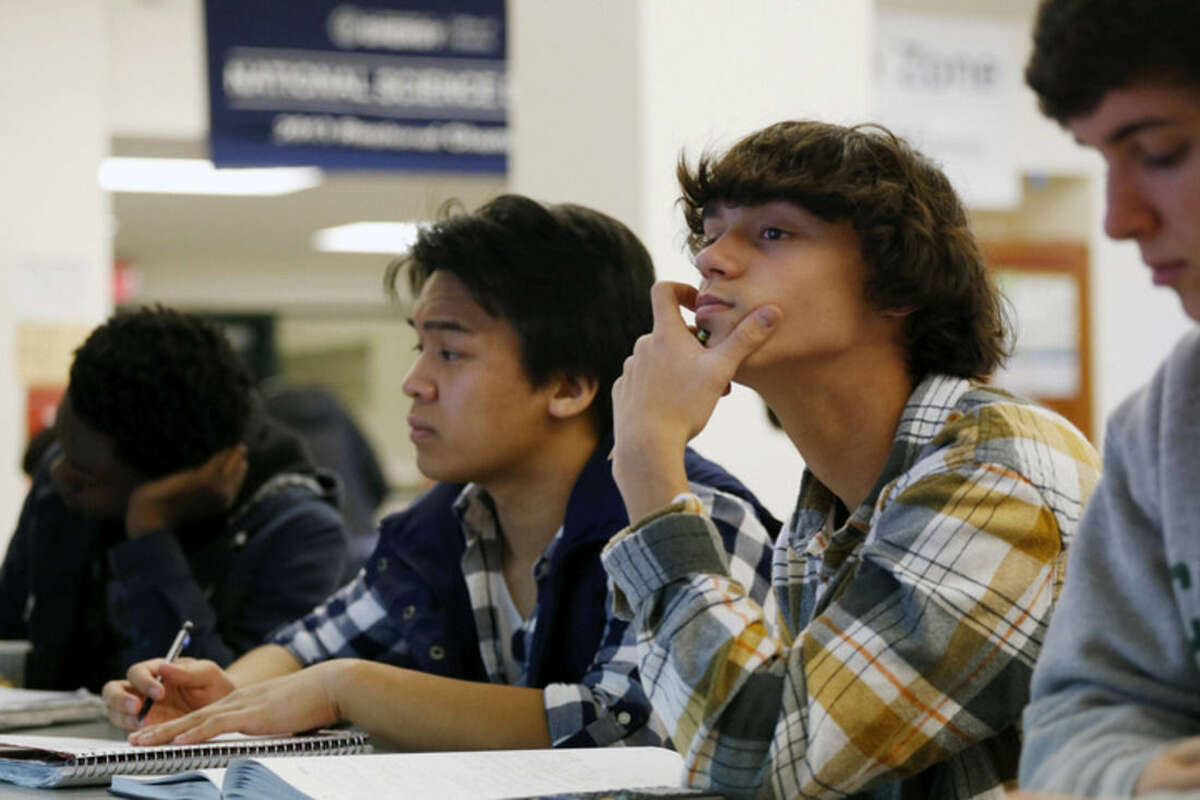 FILE - In this Feb. 7, 2014 file photo, students Julian Lopez, second left, Ben Montalbano, second right and James Agostino, right, listen during their Advanced Placement (AP) Physics class at Woodrow Wilson High School in Washington. A new policy from the American Academy of Pediatrics recommends delaying classes for all teens until at least 8:30 a.m. to curb their widespread lack of sleep, which has been linked with poor health, bad grades, car crashes and other problems. The policy was published online Monday, Aug. 25, 2014, in Pediatrics. (AP Photo/Charles Dharapak, File)