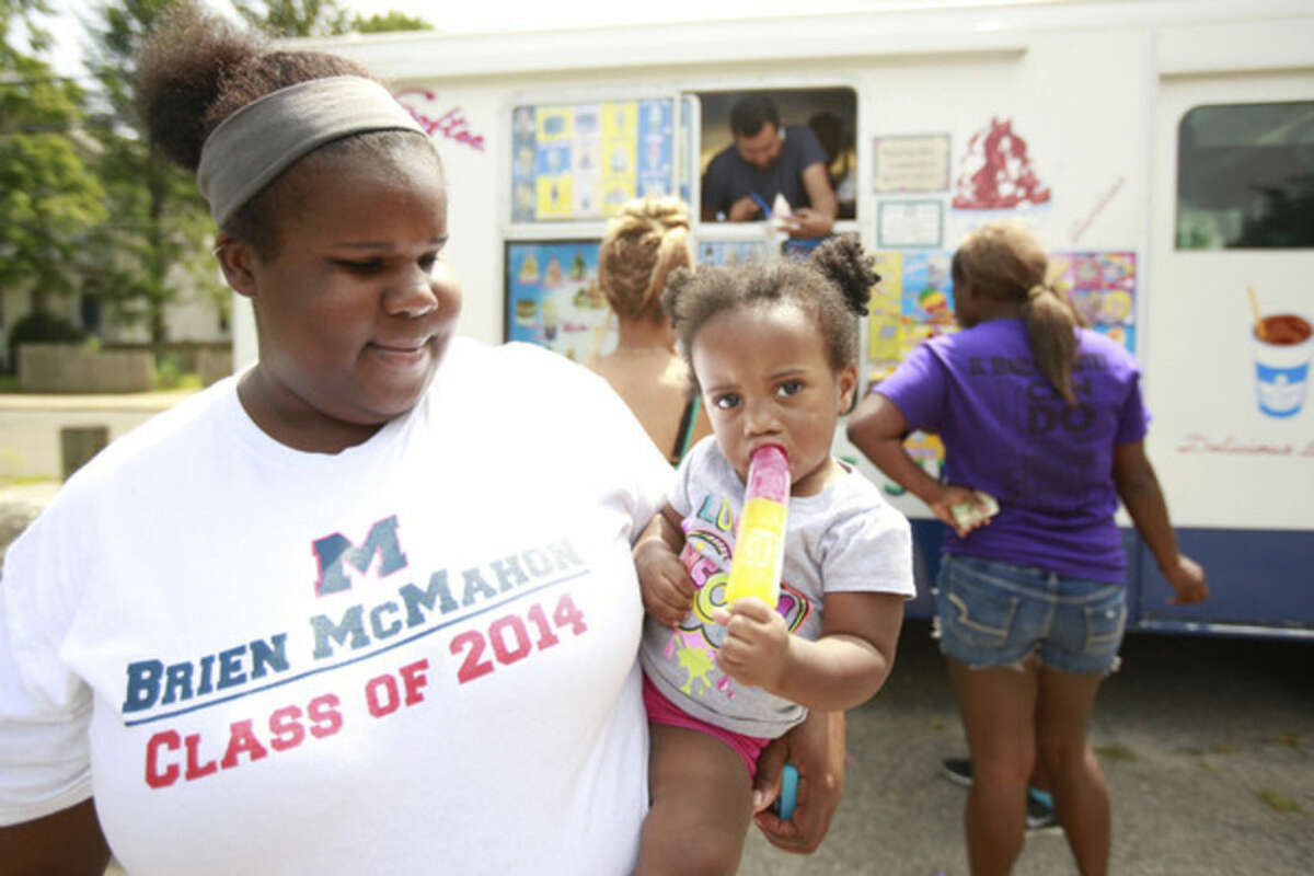 Hour photo/Chris Palermo Jordan Sanford enjoys a popsicle while being held by Kim McElveen during the community outreach event at El'Shaddai Ministry of Norwalk Saturday afternoon.