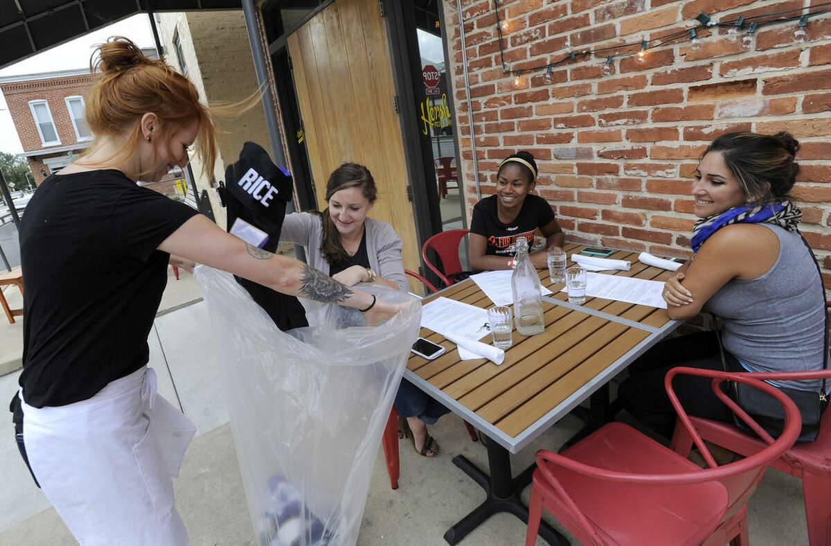 Bartender Abby Hopper, left, of Baltimore, collects a Ray Rice Baltimore Ravens football jersey from Sam DeMarco, second from left, of Baltimore, who dined with Allie Hurtt, third from left, of Baltimore, and Darya Safai, right, of Baltimore at Hersh's Pizza and Drinks, a Baltimore restaurant that offered a free personal pizza in exchange for Rice jerseys Monday, Sept. 8, 2014. Rice was let go by the Ravens on Monday and suspended indefinitely by the NFL after a video was released showing the running back striking his then-fiancee in February. (AP Photo/Steve Ruark)