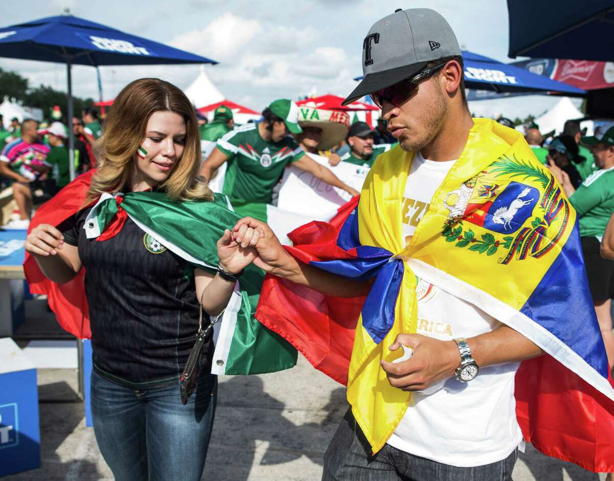 Mexico fan Alison Sifuentes, left, and Venezuela fan Carlos Paredes Aldana wear their colors Monday outside NRG Stadium before their teams meet. ﻿