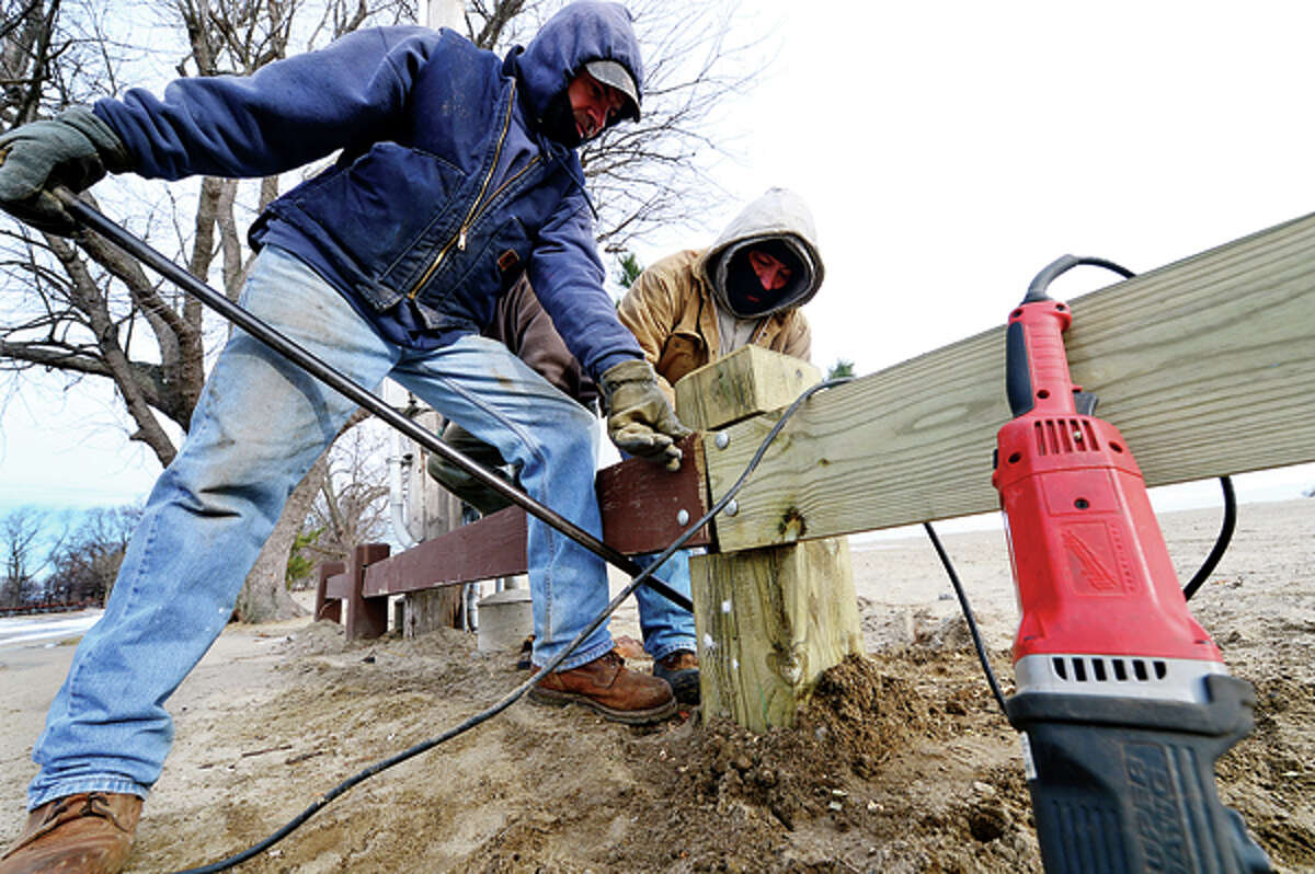 Damage from Hurricane Sandy is still apparent Tuesday as Tony Duarte and Roman Vasquez of Total Fence repair fencing at Calf Pasture Beach. Hour photo / Erik Trautmann