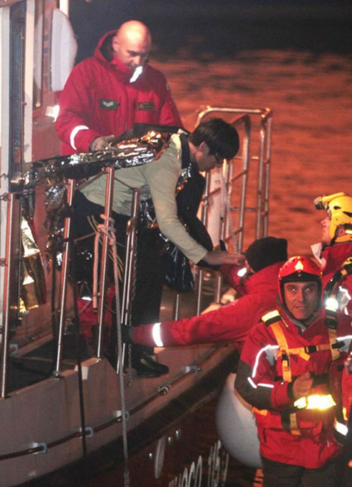 A passenger from South Korea, top left, disembarks from an Italian Firefighter boat after being rescued from the luxury cruise ship Costa Concordia which ran aground the tiny Tuscan island of Giglio, Italy, Sunday, Jan. 15, 2012. The luxury cruise ship ran aground off the coast of Tuscany, sending water pouring in through a 160-foot (50-meter) gash in the hull and forcing the evacuation of some 4,200 people from the listing vessel early Saturday, the Italian coast guard said. (AP Photo/Gregorio Borgia)