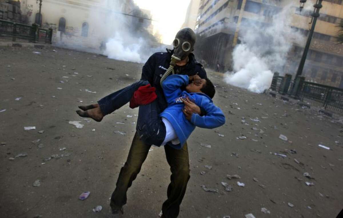 An Egyptian protester evacuates an injured boy during clashes near Tahrir Square, Cairo, Egypt, Friday, Jan. 25, 2013. Two years after Egypt's revolution began, the country's schism was on display Friday as the mainly liberal and secular opposition held rallies saying the goals of the pro-democracy uprising have not been met and denouncing Islamist President Mohammed Morsi. (AP Photo/Khalil Hamra)
