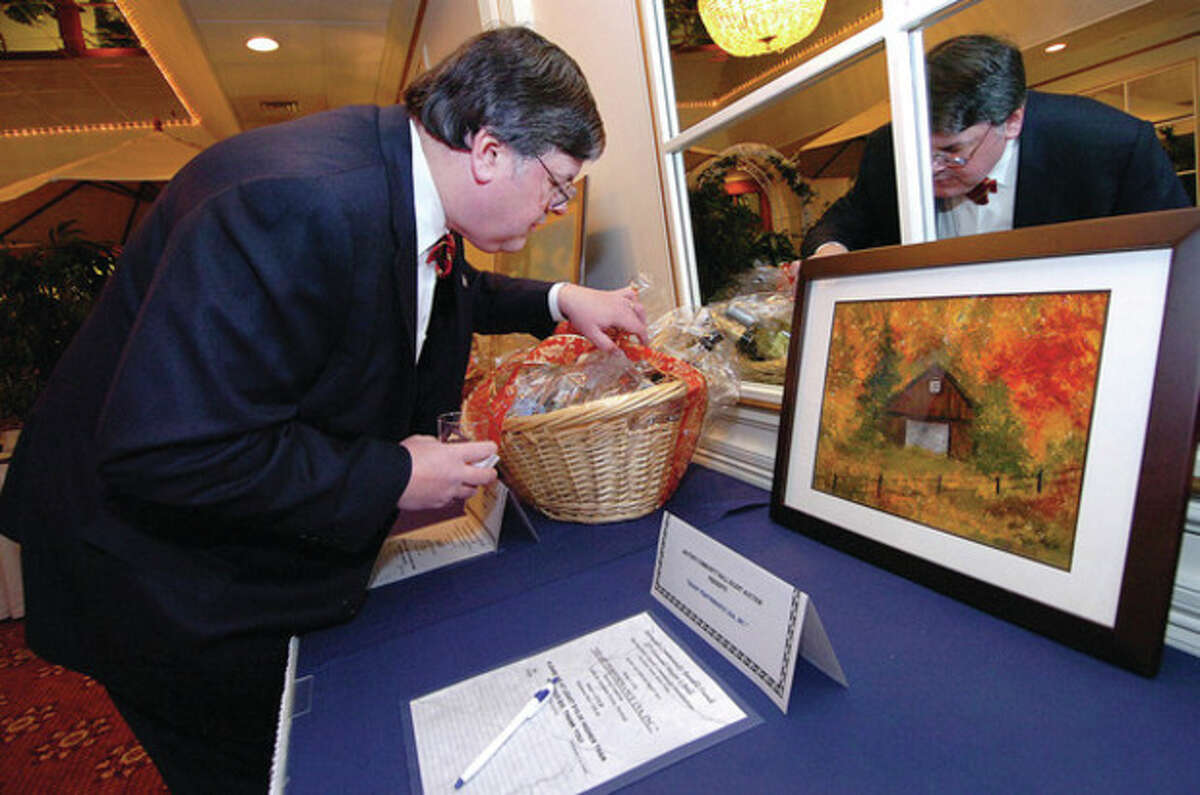 Hour Photo Alex von Kleydorff; Attorney Matt Miklave takes a close look at a gift basket of 'Adult Beverages' of Scotch, Gin and other treats donated by Diago for the Mayors Ball silent auction.