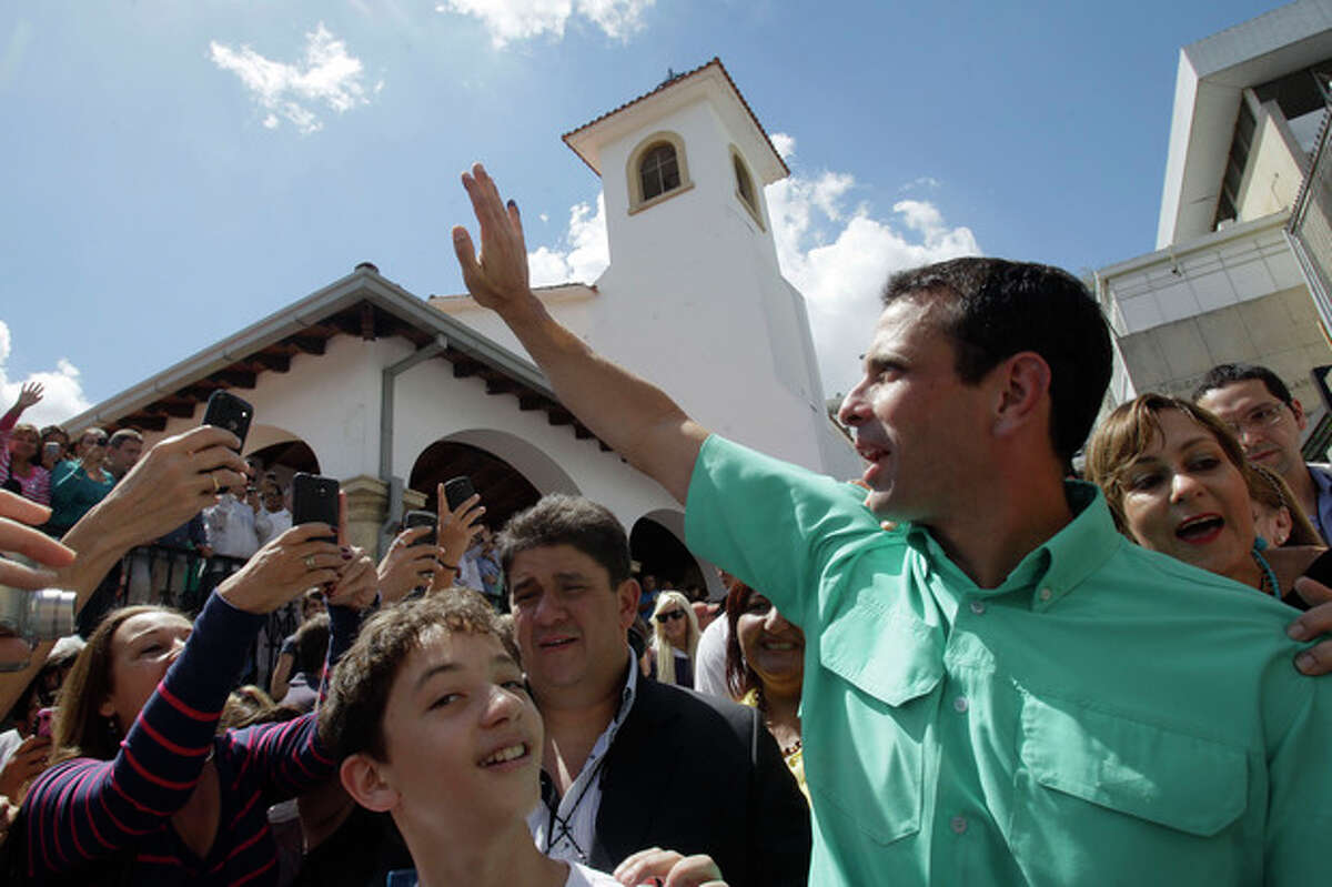 Henrique Capriles, front-runner among five opposition presidential contenders, waves to supporters outside of a polling station after casting his ballot in Caracas, Venezuela, Sunday Feb. 12, 2012. Venezuelans lined up to vote Sunday in the country's first-ever opposition presidential primary, choosing a single challenger they hope will have what it takes to defeat President Hugo Chavez in October, after 13 years in office. (AP Photo/Ariana Cubillos)