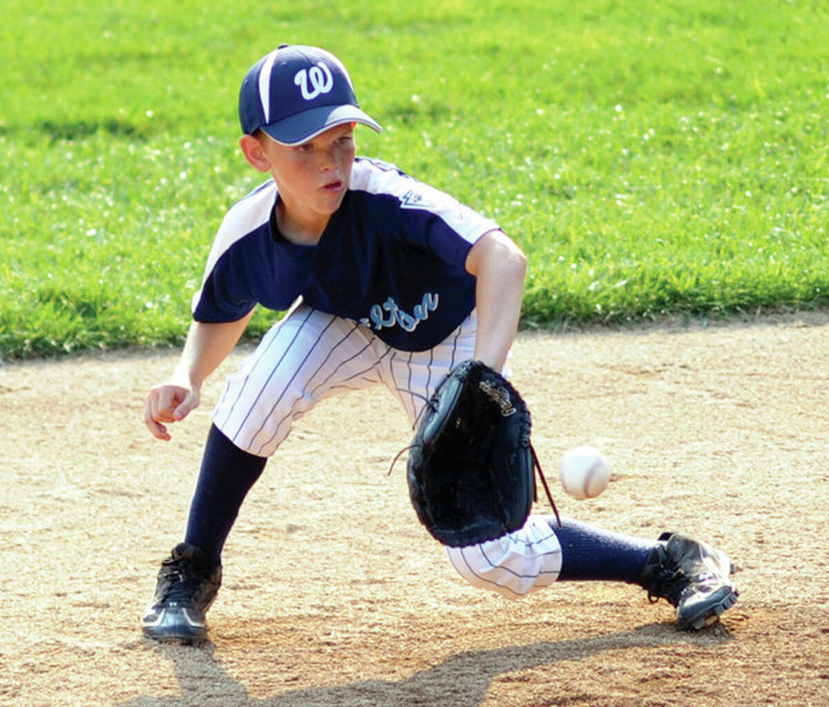 Hour Photo/John Nash Wilton?•s Zach Liston backhands a ground ball for an out during Wednesday's 10-year-old Little League pool play finale. Wilton beat Darien, 4-2.