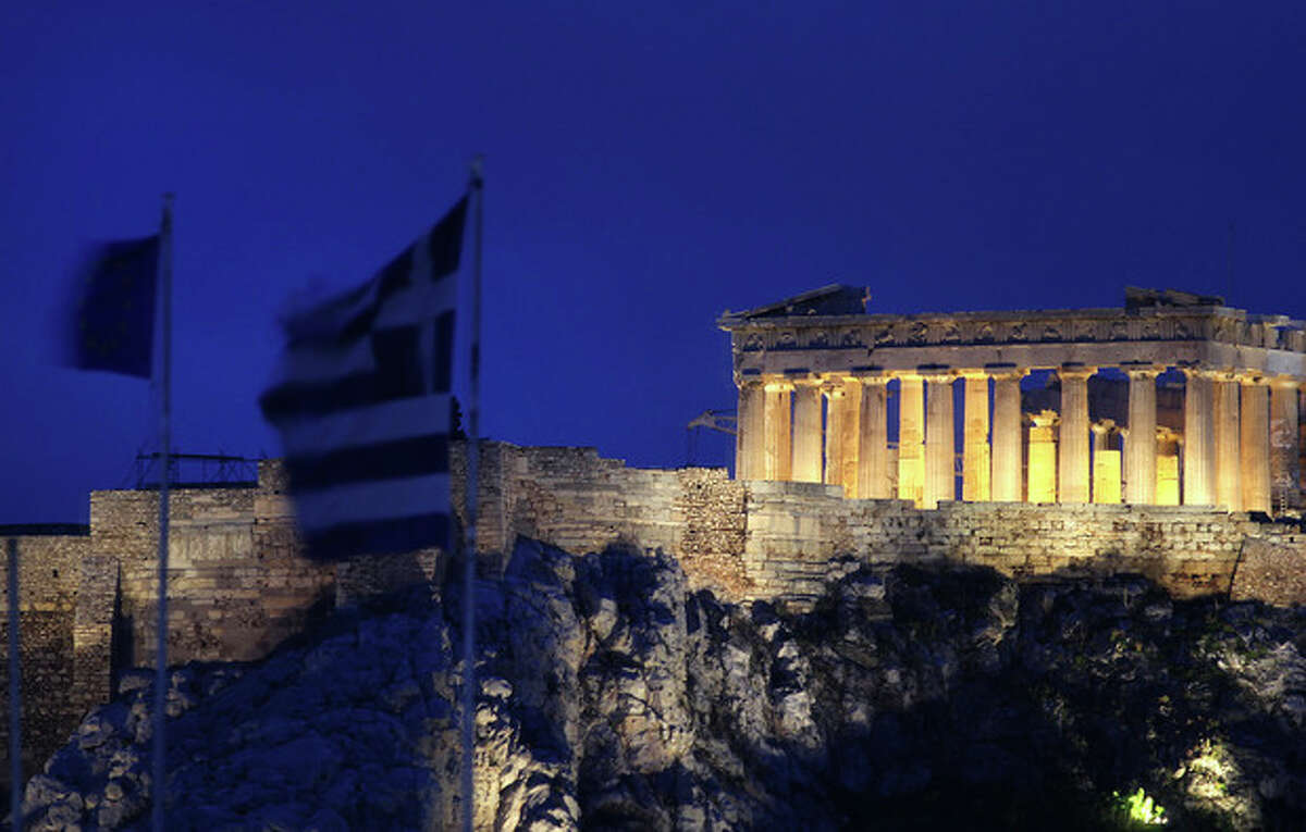 The flags of Greece, 2nd left, and European Union flutter from the roof of the Finance Minister at Athens' main Syntagma square, as in the background is seen the ancient Parthenon temple during in Athens on Thursday Feb, 9, 2012. Greece's deputy labor minister has resigned to protest demanded new austerity measures. Yiannis Koutsoukos issued a statement on Thursday saying he opposes implementation of cutbacks and reforms agreed earlier Thursday to secure the country's international rescue loan lifeline. Koutsoukos is a lawmaker with the majority Socialist party. (AP Photo/Dimitris Messinis)