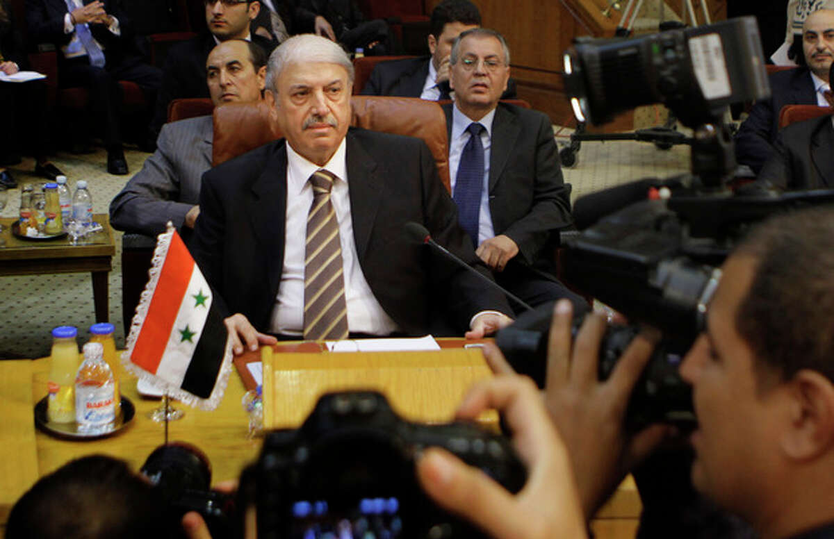 Yussef al-Ahmad, Syria's ambassador to the Arab League, is surrounded by cameramen during the Arab League emergency session on Syria at the Arab League headquarters in Cairo, Egypt, Saturday, Nov.12, 2011 . The Arab League has voted to suspend Syria from all meetings until it implements plan to end bloodshed. (AP Photo/Amr Nabil)