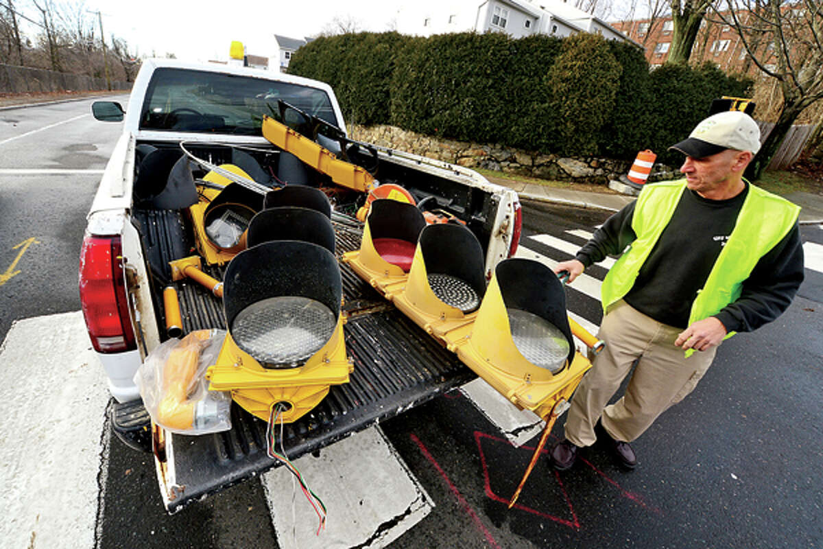 DPW Traffic Supervisor Bob Atunes removes a signal light that came down in the storm on CT Ave. Heavy winds associated with a storm that effected the area early Thursday morning brought down wires and trees throughout Norwalk. Hour photo / Erik Trautmann