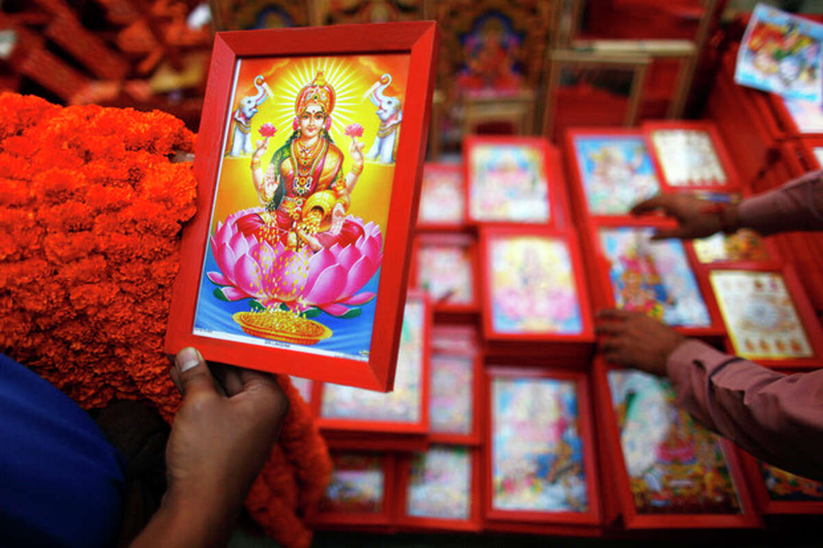 AP Photo/Niranjan Shrestha A Nepalese man selects a picture of Lakshmi, the Hindu goddess of wealth, during the second day of Tihar festival in Katmandu, Nepal, Wednesday. Nepalese are celebrating the five-day long festival of Tihar, dedicated to the worship of various animals, the Goddess Lakshmi and brothers.