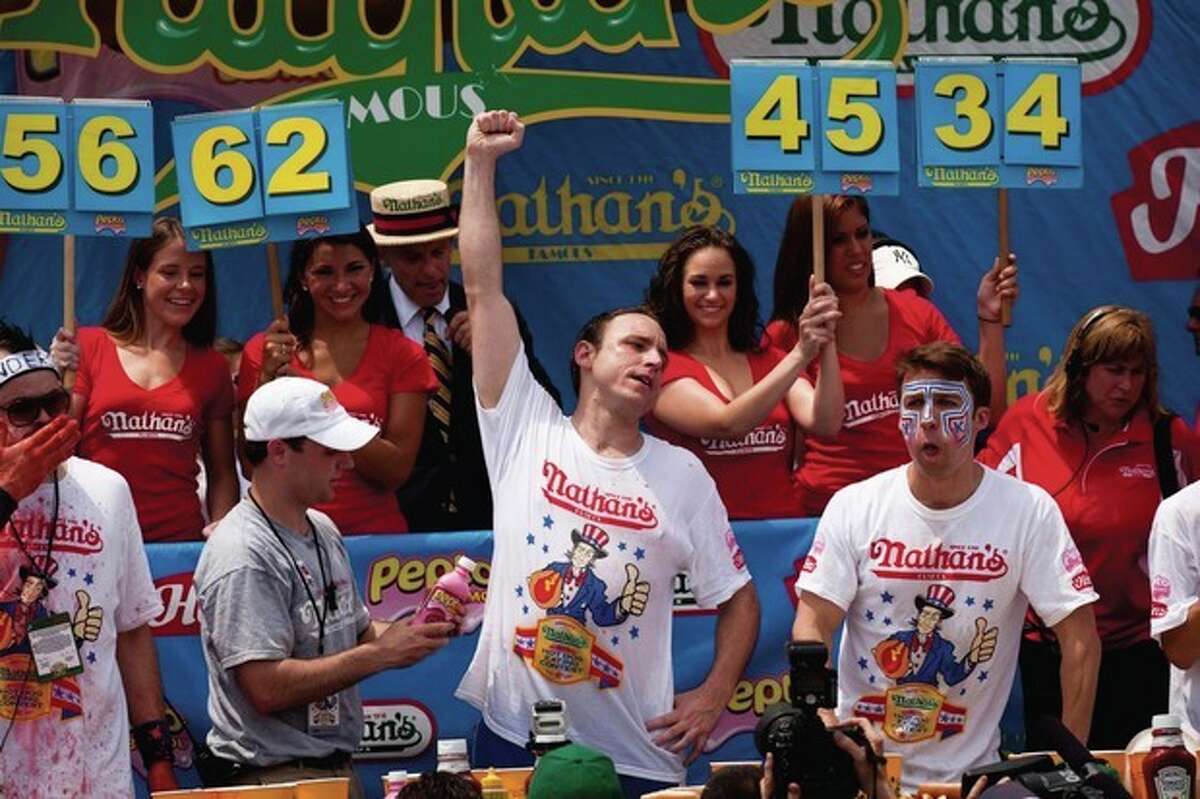 Four-time reigning champion Joey Chestnut, center, raises his arm in victory as he wins his fifth Nathan?•s Famous Hot Dog Eating World Championship with a total of 62 hot dogs and buns, Monday, July 4, 2011, at Coney Island, in the Brooklyn borough of New York. (AP Photo/John Minchillo)