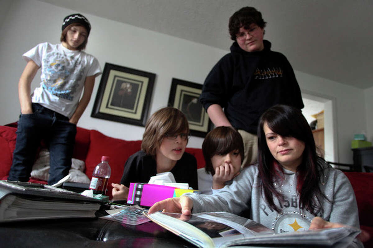 Tina Crouse, right, looks through the family scrapbook in the living room of their Christiansburg, Va. home on Saturday, Dec. 10 2011. From left are family members Dustin Crouse, 16, Tyler Robinette, 11, Peyton Robinette, 9, and Hayden Schack, 15. Officer Deriek W. Crouse was making a traffic stop when police say Ross Truett Ashley, a 22-year-old college student, walked up to his cruiser and shot him. (AP Photo/The Roanoke Times, Matt Gentry)