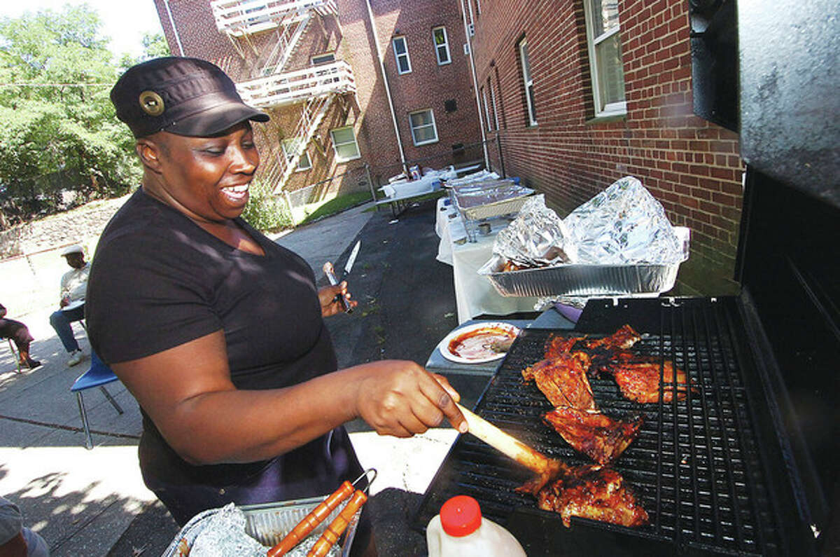 Photo/Alex von Kleydorff. Robin Peterson puts a little more barbeque sauce on the ribs and chicken during an appreciation picinic at Roodner Court on Friday.