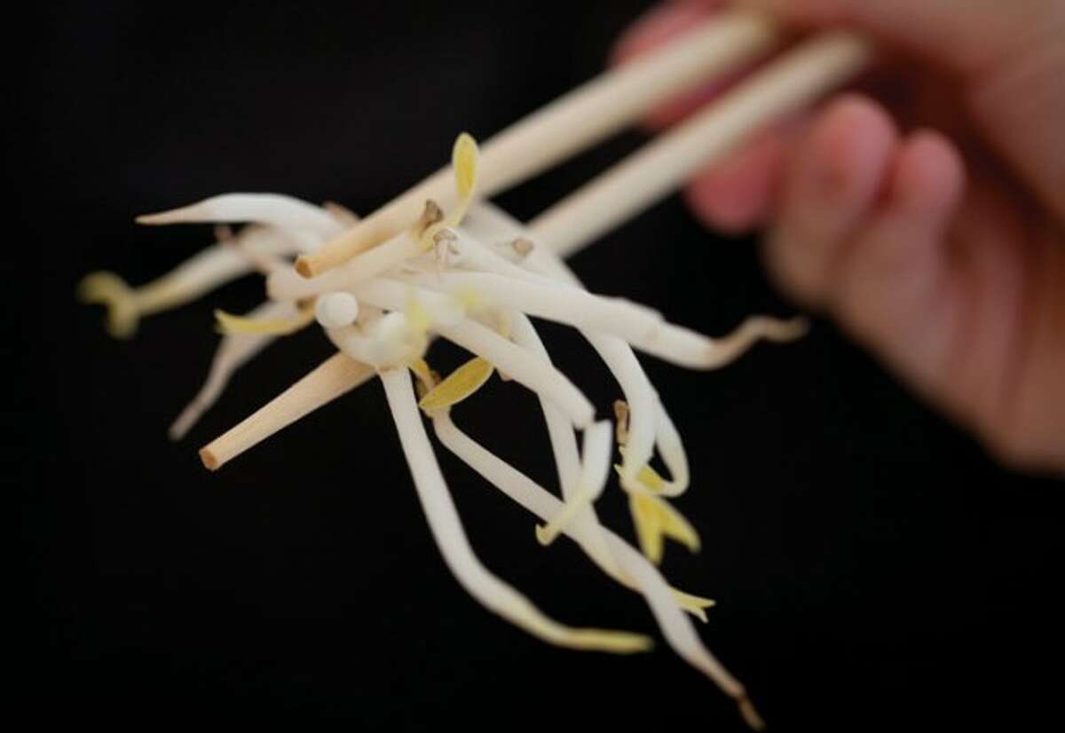 A woman holds bean sprouts with chopsticks in Berlin, Germany, Sunday, June 5, 2011. Health authorities say locally grown beansprouts in northern Germany have been identified as the likely cause of an outbreak of E. coli that has killed at least 22 people and sickened hundreds in Europe. (AP Photo/Gero Breloer)