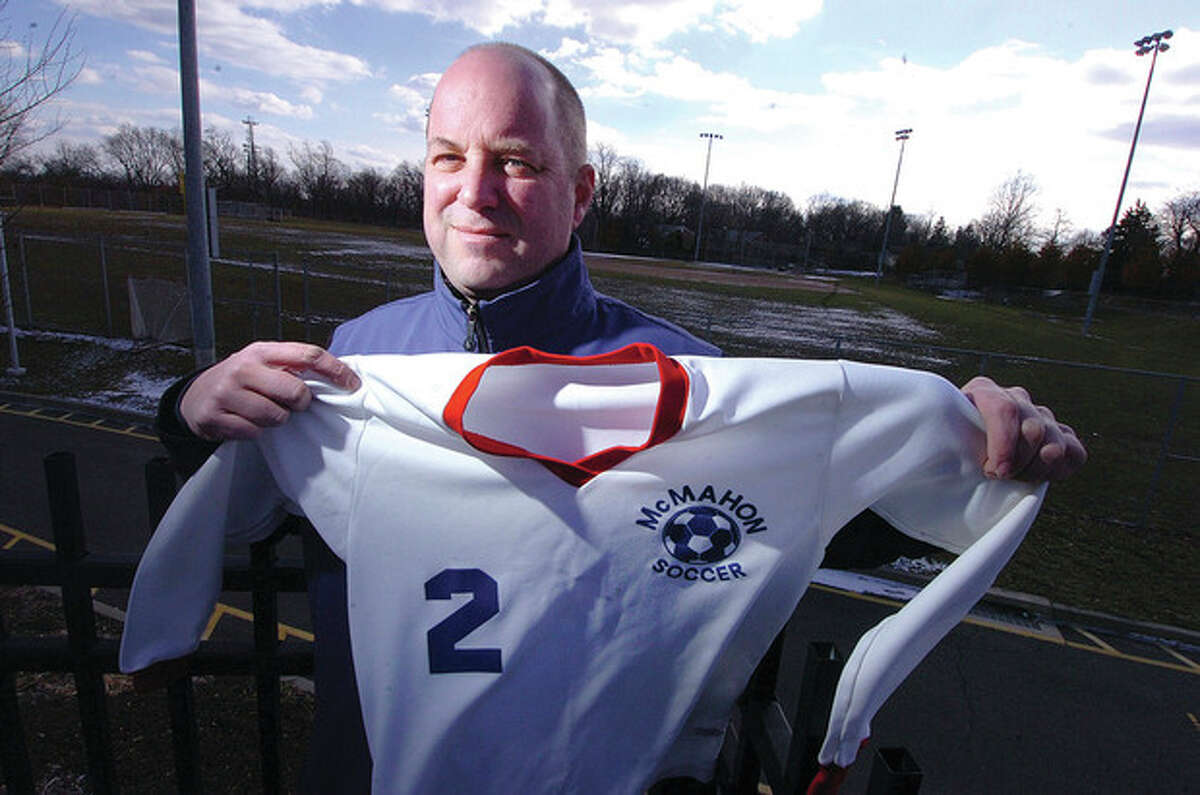 Hour photo/Alex von Kleydorff Billy Pank, who was named MVP of The Hour's first All-City Soccer Team in 1985, displays the Brien McMahon jersey he once wore while standing in front of the soccer field he used to play on.
