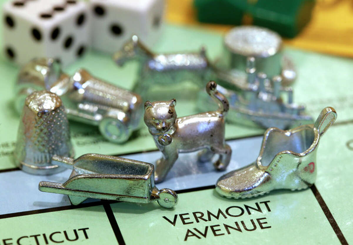 The newest Monopoly token, a cat, center, rests on a Boardwalk deed next to other tokens still in use including the wheelbarrow, left, and the shoe, right, at Hasbro Inc. headquarters, in Pawtucket, R.I., Tuesday, Feb. 5, 2013. Voting on Facebook determined that the cat would replace the iron token. (AP Photo/Steven Senne)