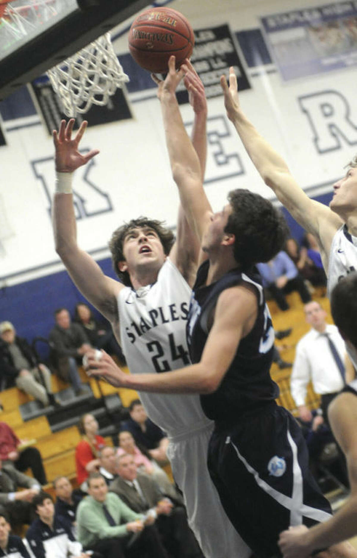Hour photo/Matthew Vinci Ross Whelan of Staples, left, goes up for a shot despite the defensive efforts of Wilton's Weston Wilbur. The Wreckers won Tuesday's game, 54-49.