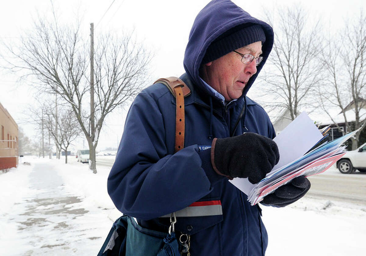 Mail carrier Bruce Nicklay walks along East Third Street in Winona, Minn., delivering letters to homes Wednesday, Feb. 6, 2013. The U.S. Postal Service will stop delivering mail on Saturdays but continue to deliver packages six days a week under a plan aimed at saving about $2 billion annually, the financially struggling agency says. (AP Photo/Winona Daily News, Andrew Link)