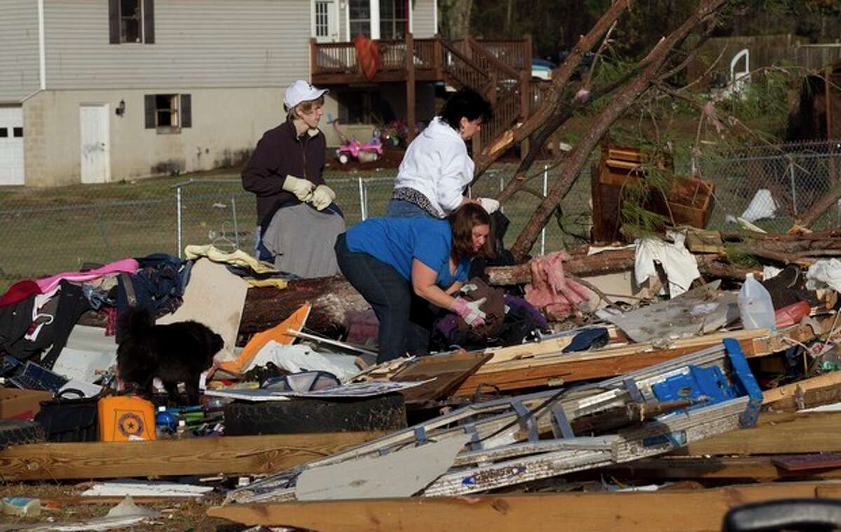 Neighbors and friends pick through the remains of Russ and Amber Butler's home in Oak Grove, Ala., Monday, Jan. 23, 2012 after a possible tornado passed through the area. Homes were flattened, windows were blown out of cars and roofs were peeled back in the middle of the night in the community of Oak Grove near Birmingham. (AP Photo/Dave Martin)