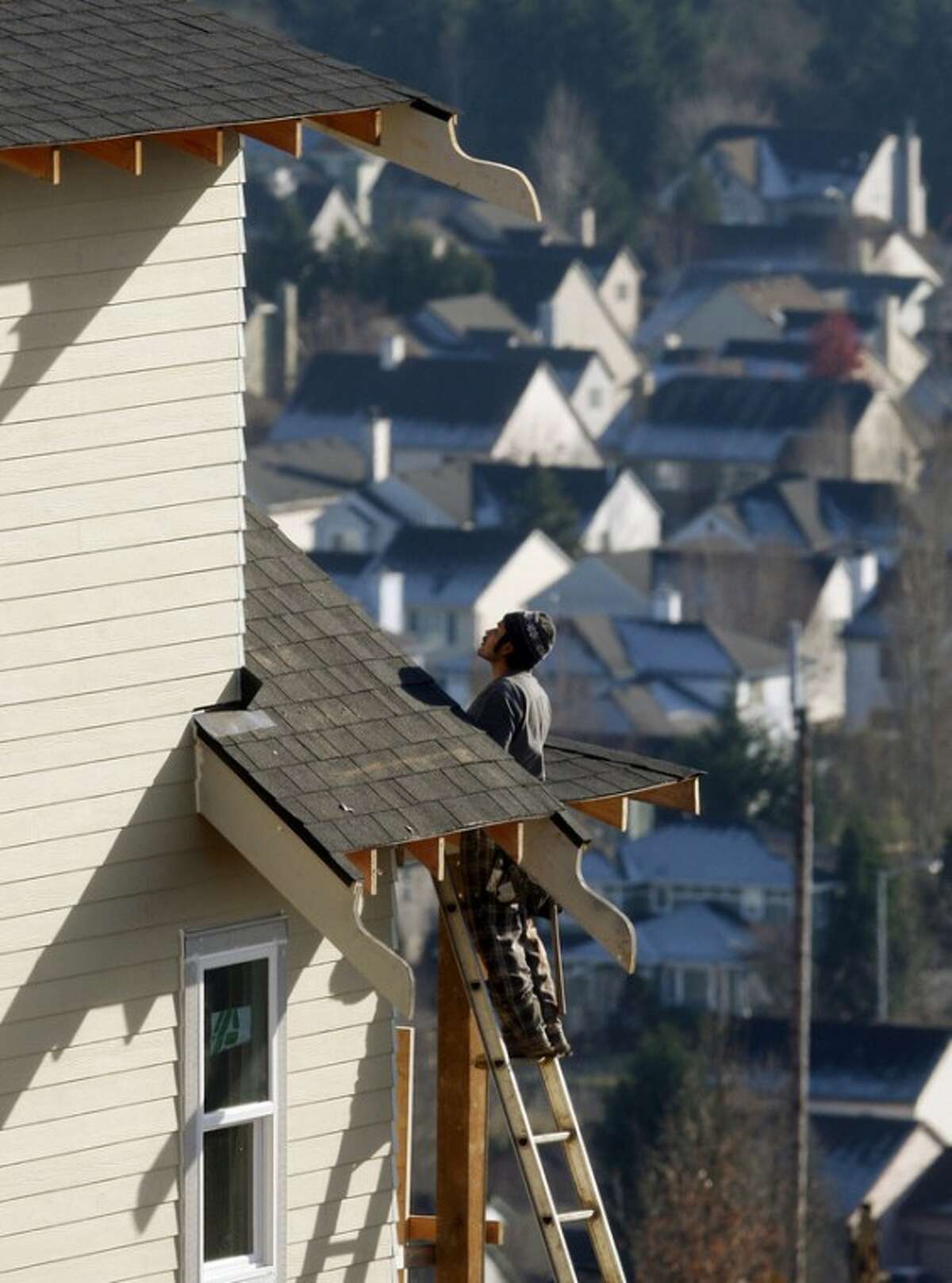 In this Dec. 20, 2011 photo, a carpenter works on a roof of a home in Happy Valley, Ore. U.S. home prices fell in most major cities for the second straight month, further evidence that the housing recovery will be bumpy. (AP Photo/Rick Bowmer)