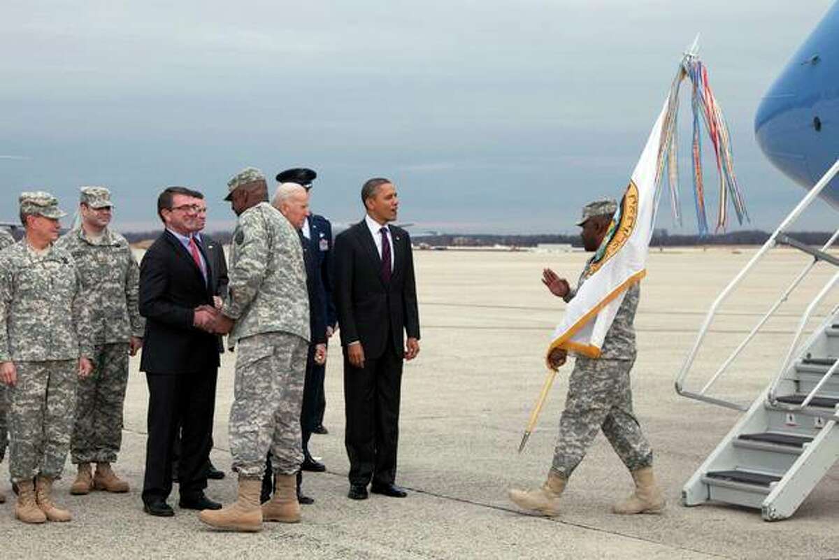 FILE - In this Dec. 20, 2011 file photo, President Barack Obama, second from right, and Vice President Joe Biden, third from right, join Deputy Secretary of Defense Ashton B. Carter, third from left, and Chairman of the Joint Chiefs of Staff Gen. Martin E. Dempsey, left to greet a member of the military as he steps off a plane with the United States Forces-Iraq Colors at Andrews Air Force Base, Md., during a ceremony marking the return of the United States Forces-Iraq Colors and the end of the war in Iraq. For now, there are no plans to hold a huge ticker-tape parade for troops returning from Iraq, no arrangements for a grand, flag-waving, red-white-and-blue homecoming of the sort America's fighting men and women received after World War II and the Gulf War. (AP Photo/Carolyn Kaster, File)