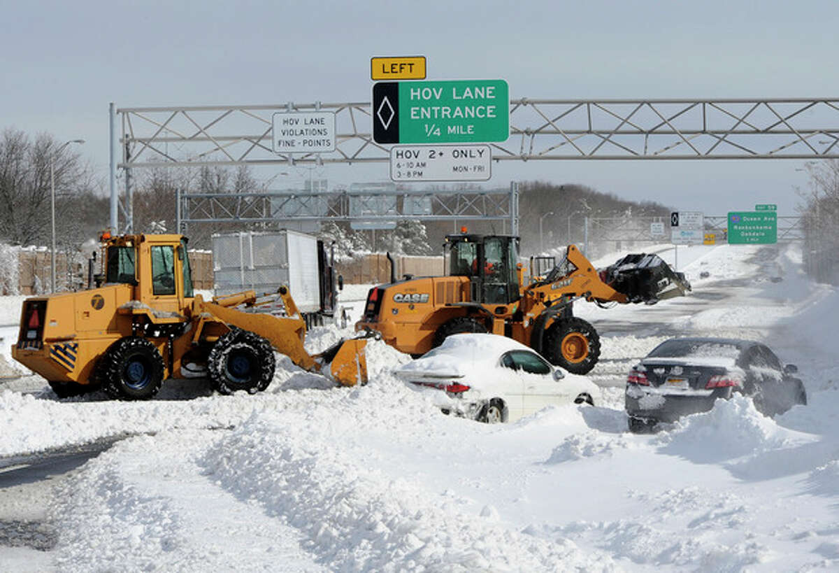 Payloaders clear snow from the Long Island Expressway just west of exit 59 Ocean Ave where several cars and a truck are abandoned after a snow storm on Saturday, Feb. 9, 31, 2013, in Ronkonkoma , N.Y. (AP Photo/Kathy Kmonicek)