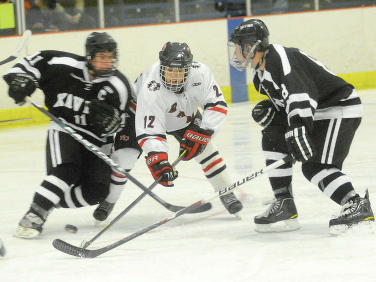 Hour photo/Matthew Vinci New Canaan's Danny Newman tries to force his way past Xavier defenders Dan Dupont, left, and Dakota Caron during Monday's game at Darien Ice Rink. hjkhljk