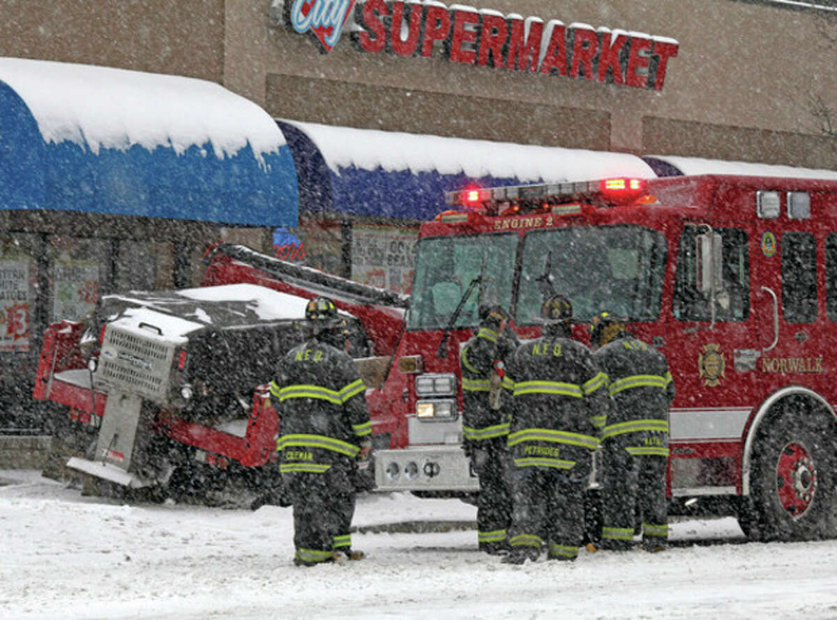 Firefighters respond to an accident that happened just outside of City Market on West Avenue in Norwalk Saturday morning during the snow storm. Hour Photo / Danielle Robinson