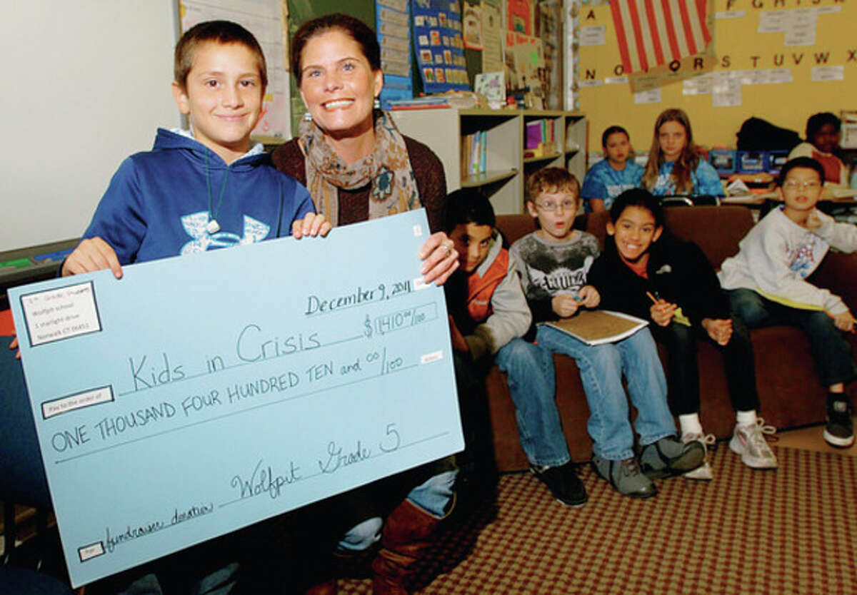 Hour photo / Erik Trautmann Wolfpit Elementary School fifth-grader Samuel White presents "Kids in Crisis" Managing Director of Development Mary Vinton with more than $1,400 the fifth-grade raised with their talent show and concession.