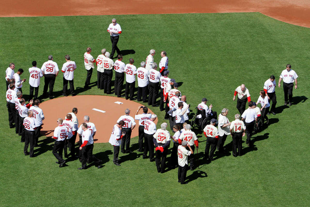 Former Boston Red Sox players, mangers and coaches gather on the field during ceremonies to celebrate the 100th anniversary of the first regular season baseball game at Fenway Park, before a game between the New York Yankees and the Red Sox in Boston, Friday, April 20, 2012. (AP Photo/Michael Dwyer)