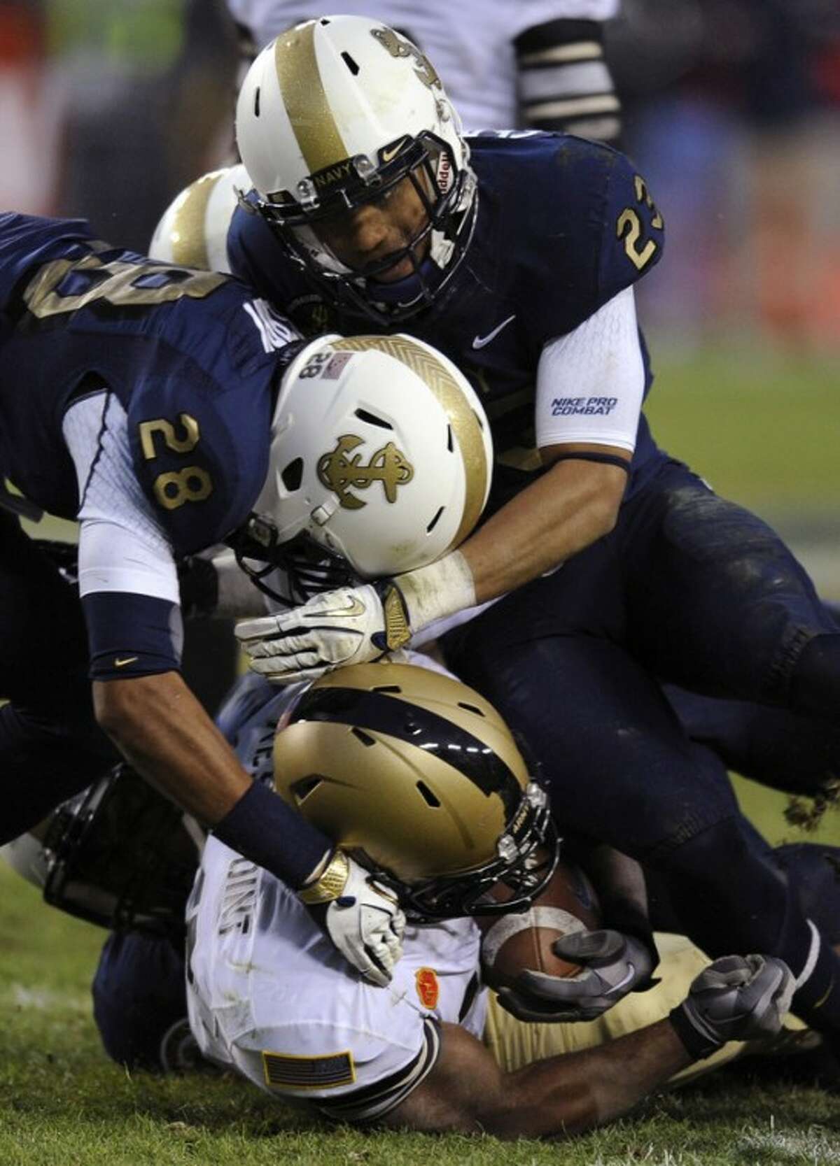 Navy defenders David Sperry (28) and Eric Graham (23) tackle Army running back Larry Dixon in the second half of an NCAA college football game in Landover, Md., Saturday, Dec. 10, 2011. (AP Photo/Nick Wass)