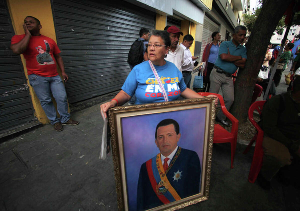 A woman holds a painting of President Hugo Chavez as supporters gather around Bolivar square after his return to the country in Caracas, Venezuela, Monday, Feb. 18, 2013. Chavez returned to Venezuela early Monday after more than two months of medical treatment in Cuba following cancer surgery. The government didn't offer an explanation as to why Chavez made his surprise return while he is undergoing other treatments that have not been specified.(AP Photo/Fernando Llano)