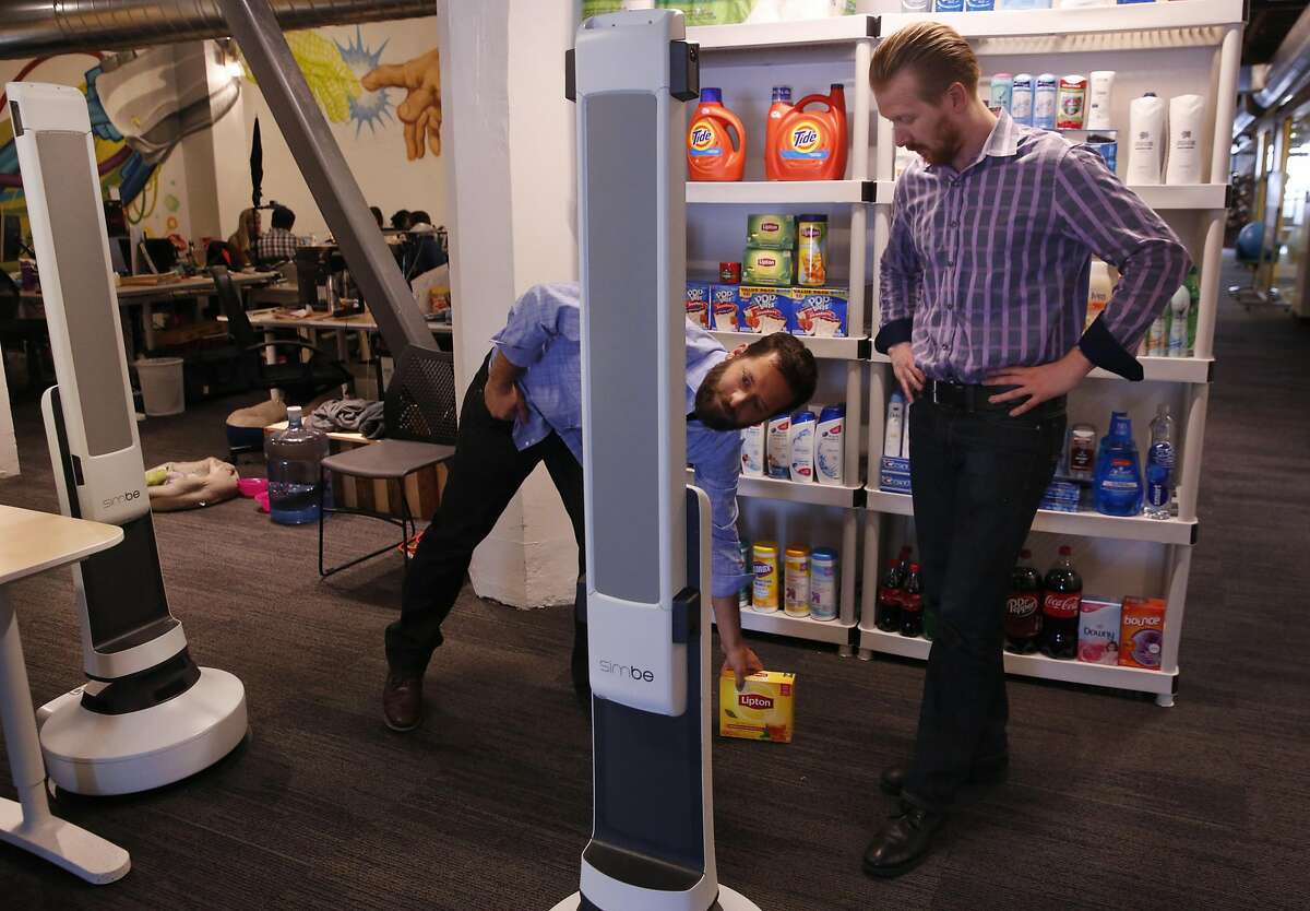 Jeff Gee, Chief of Design and Co-Founder of Simbe, left, and Brad Bogolea, CEO & Founder place a box in front of their shelf-auditing robot Tally as it rolls around to show that it will not run into the object during a demonstration at Simbe's office space June 10, 2016 in San Francisco, Calif.