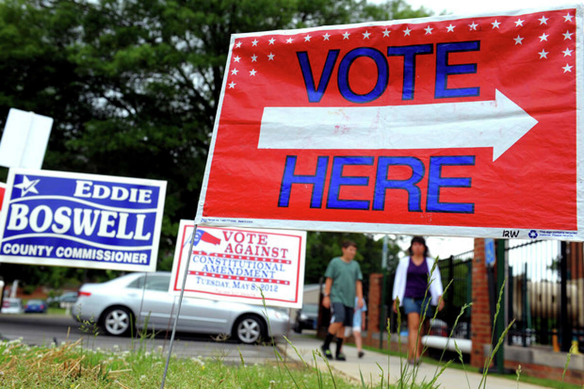 Signs are displayed at the First Presbyterian Church in Burlington, N.C., on Tuesday May 8, 2012, as people approach the building to cast their ballots. North Carolina could be the next state to pass a constitutional amendment defining marriage as solely between a man and a woman. Voters are casting their ballots Tuesday. (AP Photo/Burlington Times-News, Sam Roberts)