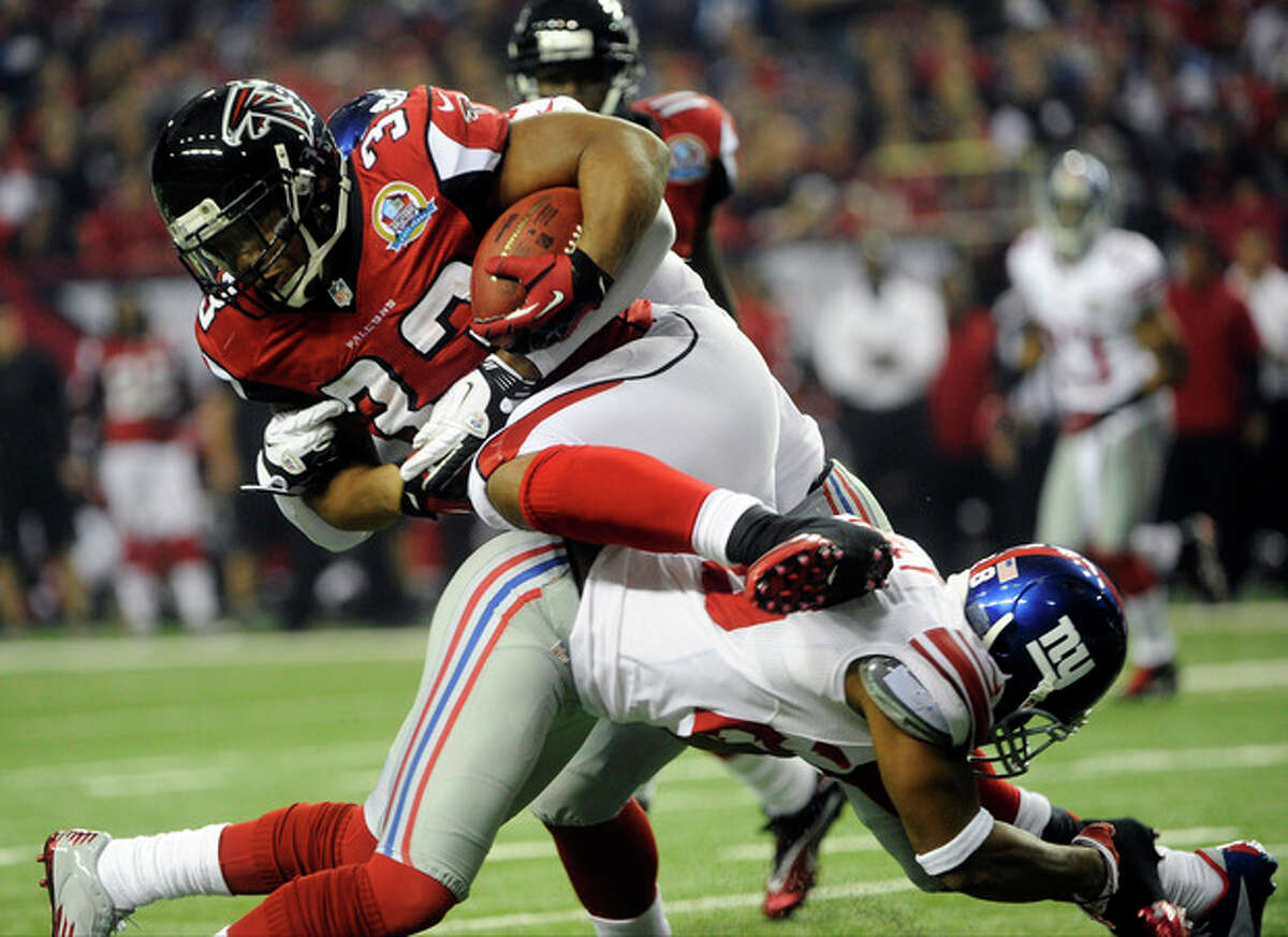 FILe - In this Dec. 16, 2012 file photo, Atlanta Falcons running back Michael Turner (33) runs over New York Giants linebacker Adrian Tracy (98) during the first half of an NFL football game in Atlanta. (AP Photo/John Amis, File)