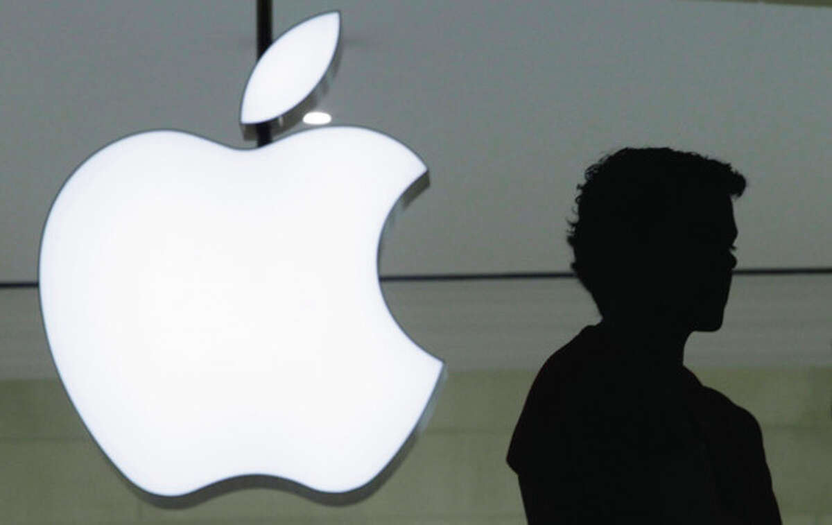 In a Wednesday, Dec. 7, 2011 file photo, a person stands near the Apple logo at the company's new store in Grand Central Terminal, in New York. If Apple had been added to the Dow in June 2009, the last time there were serious rumors that it would happen, the average would be about 2,500 points higher than it is today and well above its all-time high.(AP Photo/Mark Lennihan, File)