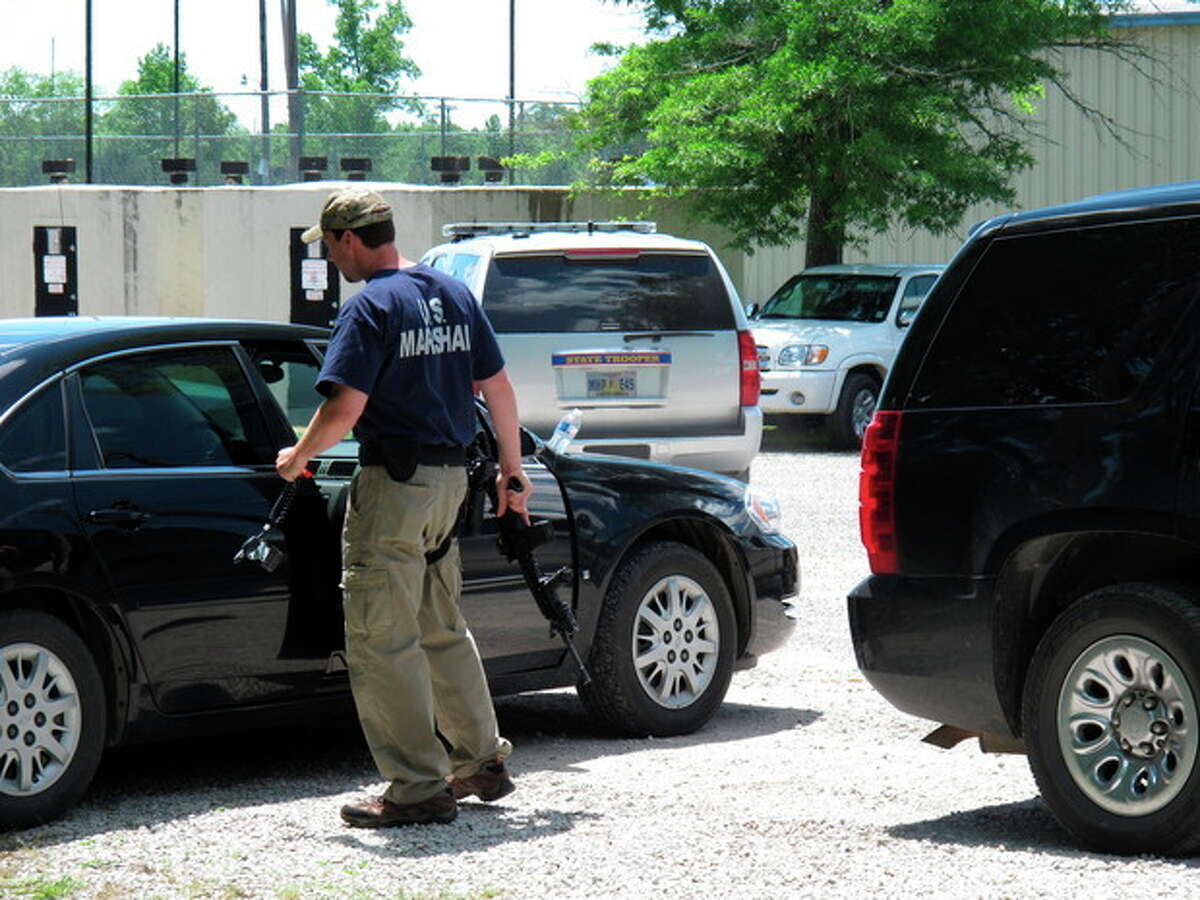 A U.S. Marshal stands next to his car holding a rifle in the parking lot of a command center set up to coordinate the search for two Tennessee girls and the man accused of abducting them and killing their mother and sister on Thursday May 10, 2012, in Guntown, Miss. The hunt for Adam Mayes and the two young sisters he is accused of kidnapping has encompassed parts of at least three counties in northern Mississippi. (AP Photo/Adrian Sainz)